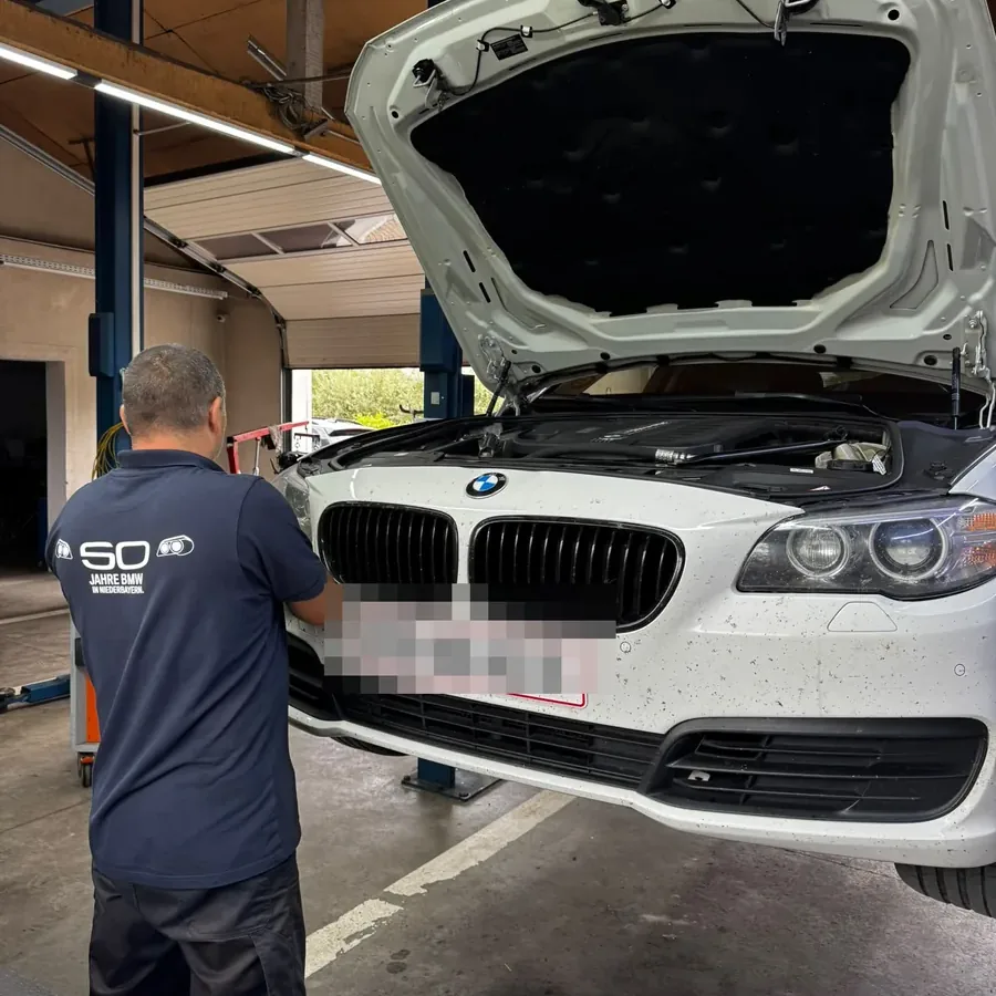 Mecanic verificând partea frontală a unui BMW pe elevator